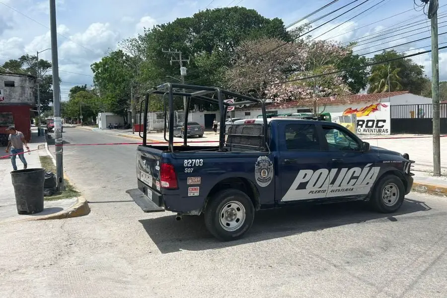 A police pickup truck parked on the side of a street in a sunny urban setting with people and buildings in the background.