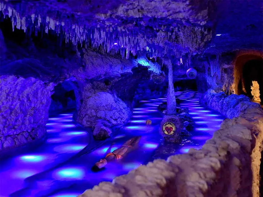 An illuminated cave with stalactites and blue lighting creating a magical underground landscape.