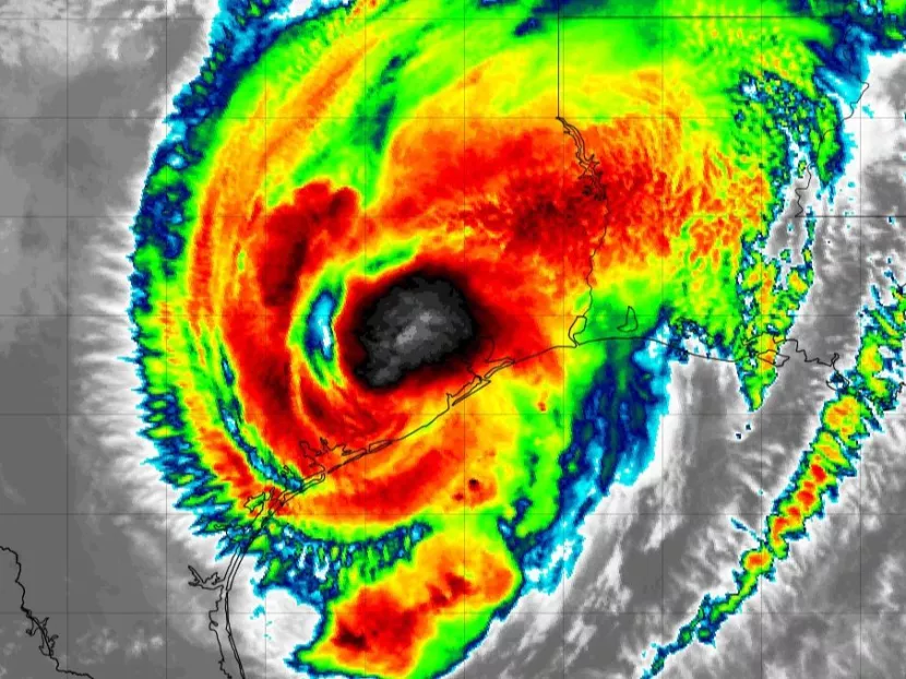 Satellite image showcasing the colorful thermal imagery of a hurricane with its distinct eye, surrounded by swirling cloud bands.
