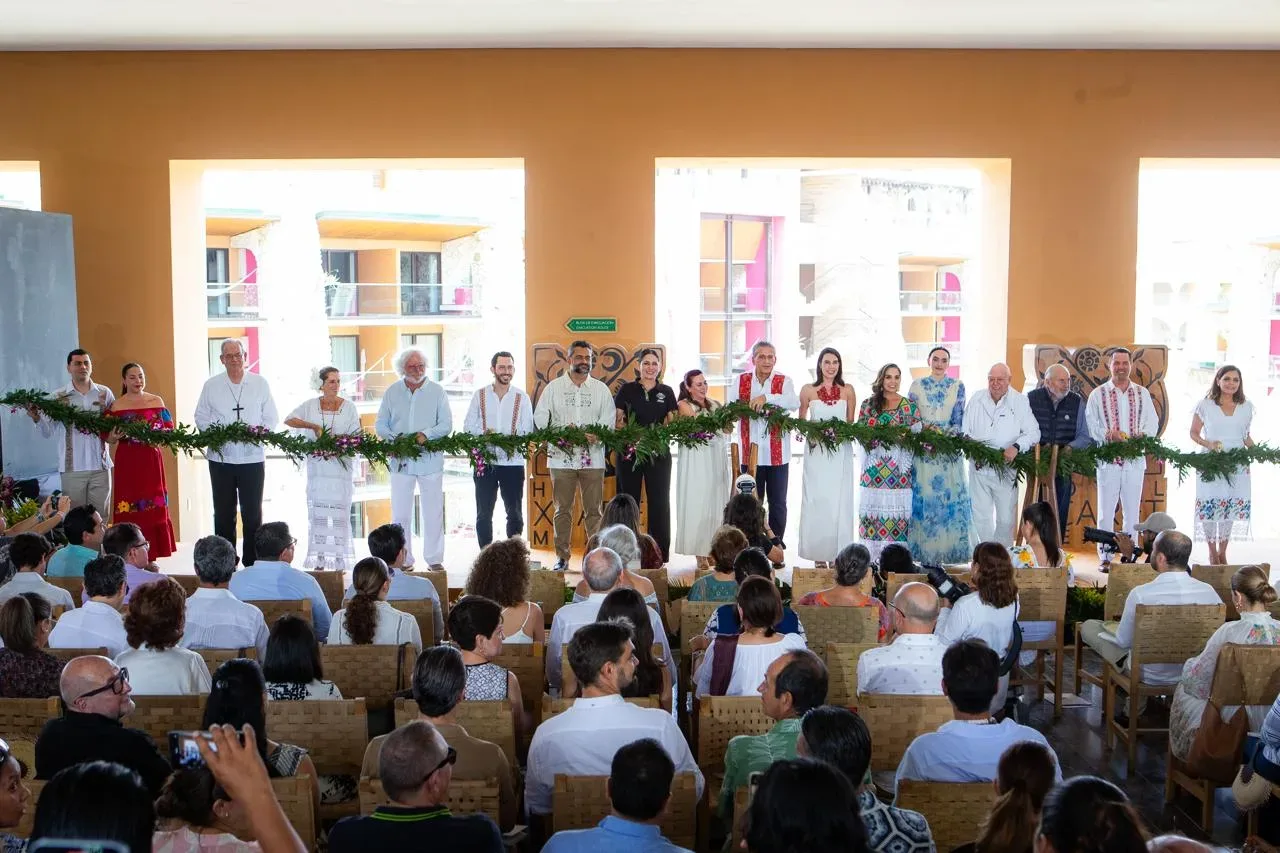 A group of individuals in traditional attire standing together at a cultural event, holding decorations while an audience watches.$# CAPTION