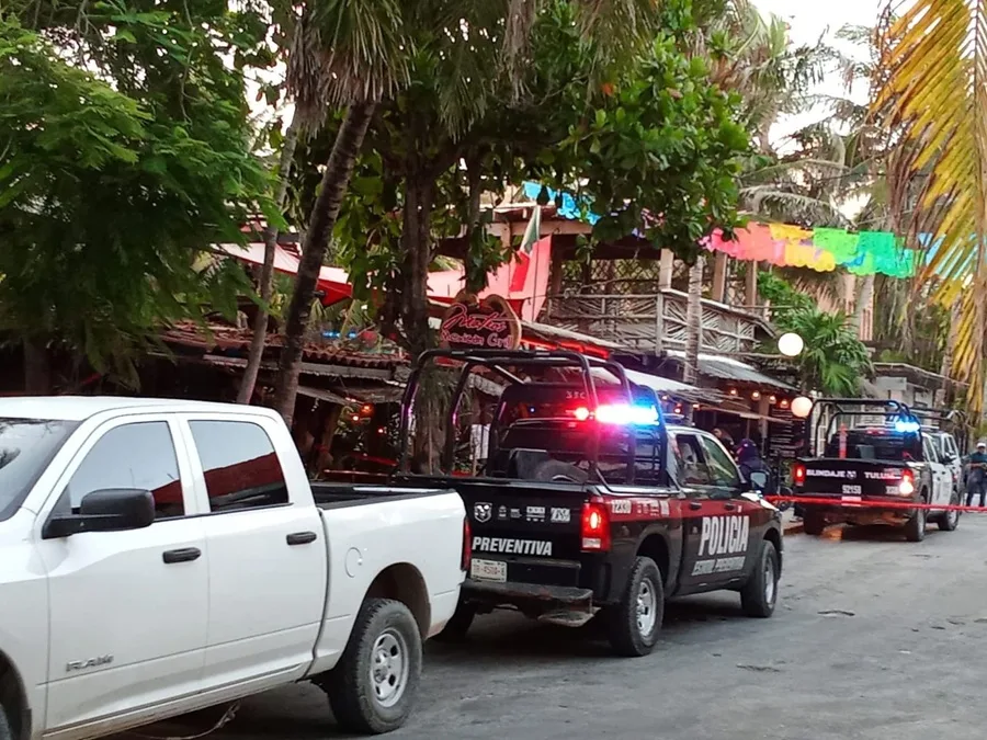 A street scene featuring multiple police vehicles and a restaurant in the background with palm trees and festive decorations.$# CAPTION
