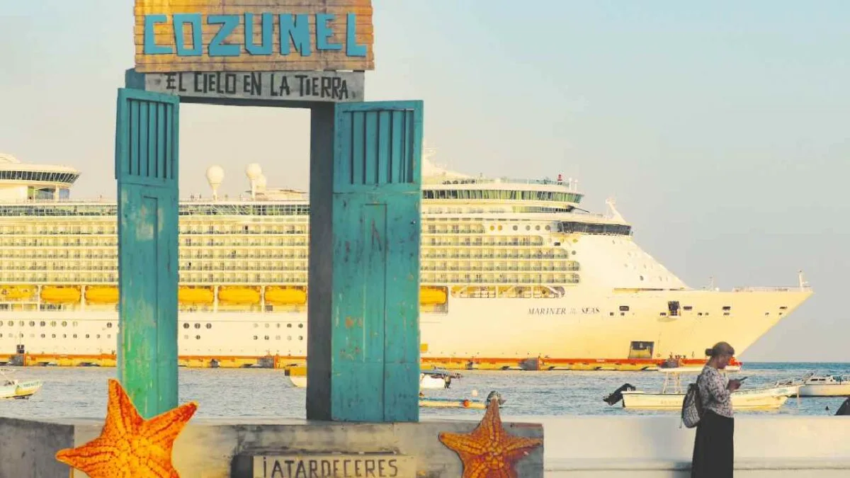 A view of Cozumel with a large cruise ship in the background and a person standing nearby, framed by an archway with the name "Cozumel."