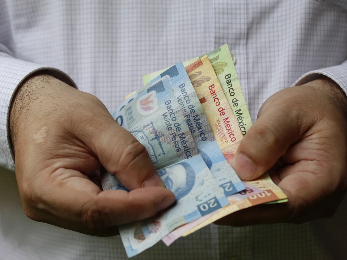 hands of a man holding mexican banknotes