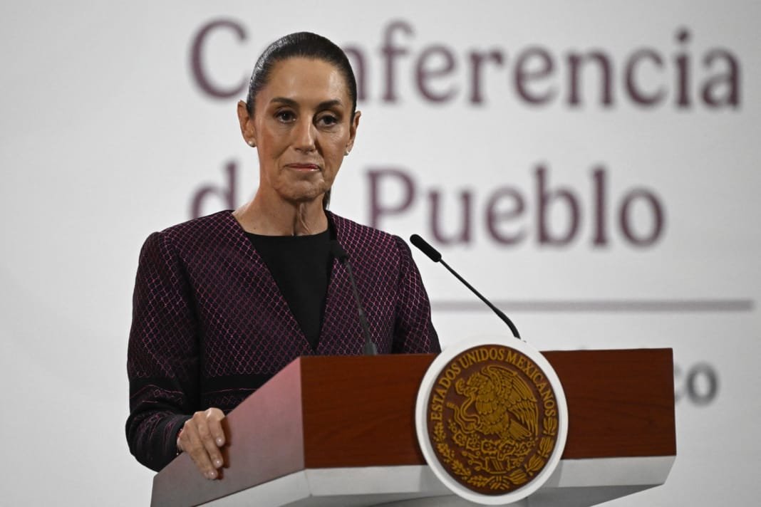A government official delivers a speech during a press conference, standing at a podium with the national emblem in the foreground and a backdrop featuring the words "Conferencia de Pueblo."