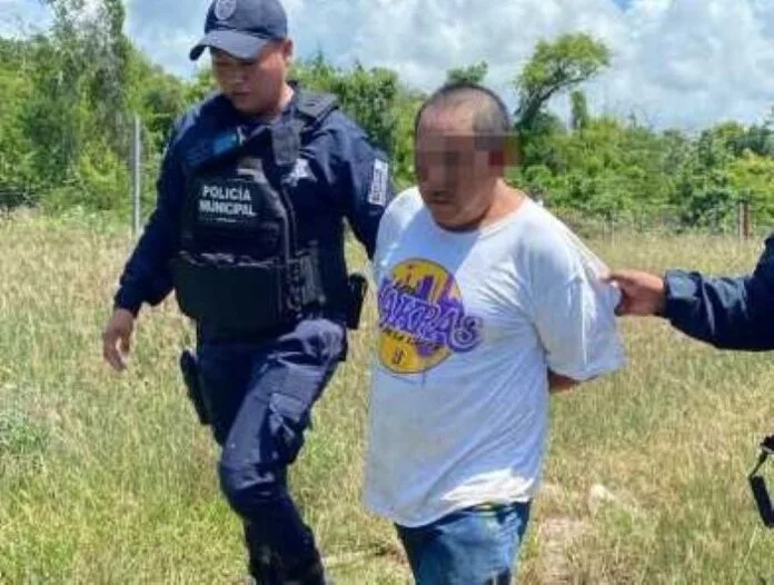 A police officer leads a handcuffed individual through a grassy area, with trees and a cloudy sky in the background.$# CAPTION
