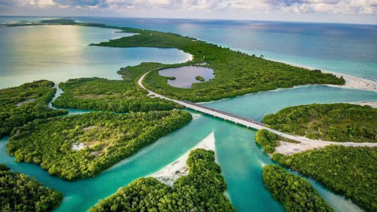 An aerial view showcasing a network of lush green islands surrounded by clear, turquoise waters and a winding road connecting them.$# CAPTION