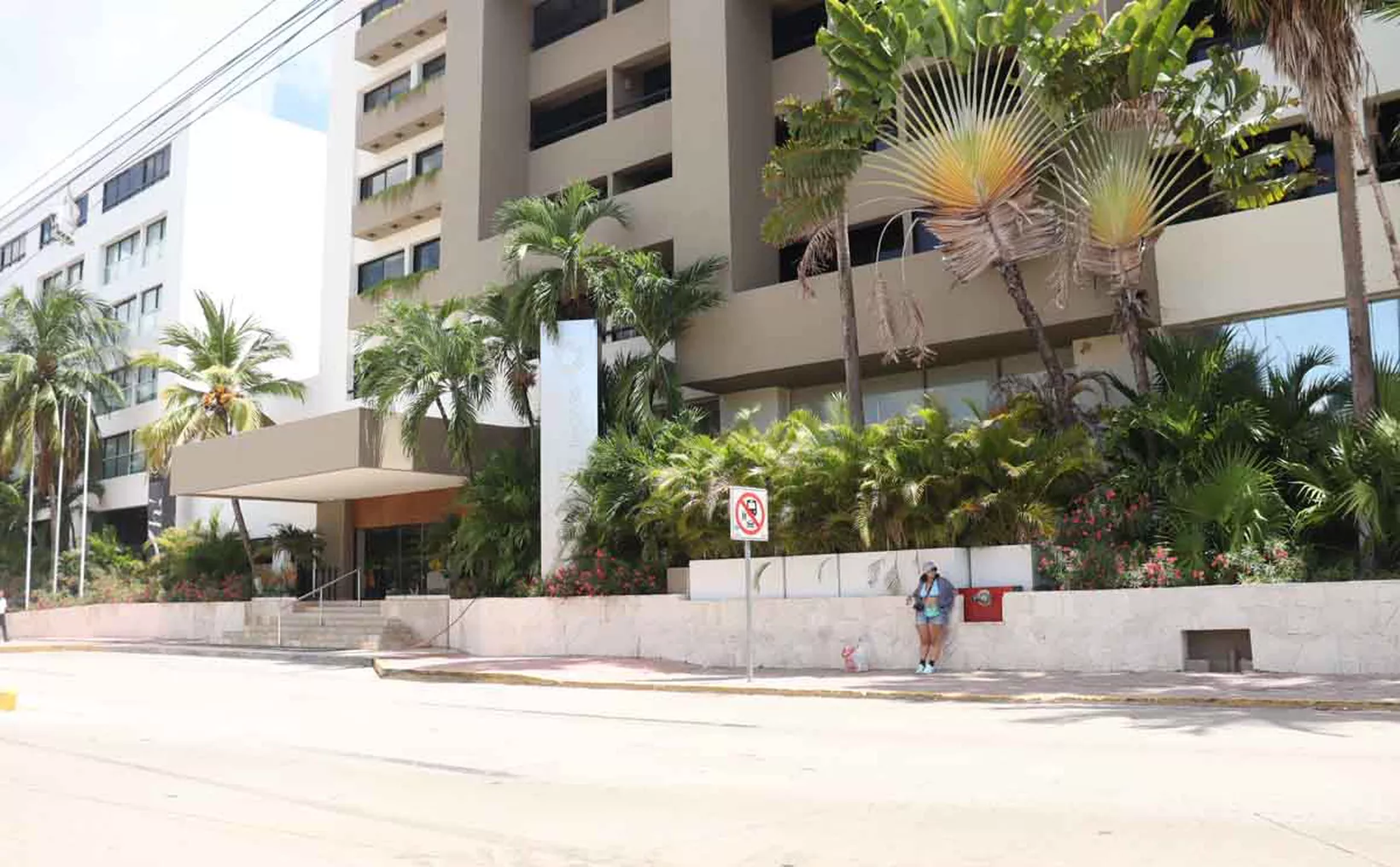 A sunny day outside a contemporary hotel, highlighting its elegant architecture and vibrant greenery.