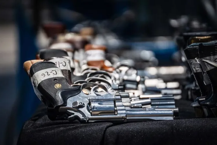 A collection of revolvers lined up on a black table, showcasing various models and grips.$# CAPTION