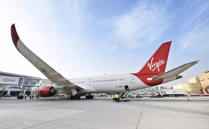 A Virgin Atlantic airplane parked on the tarmac with ground crew present