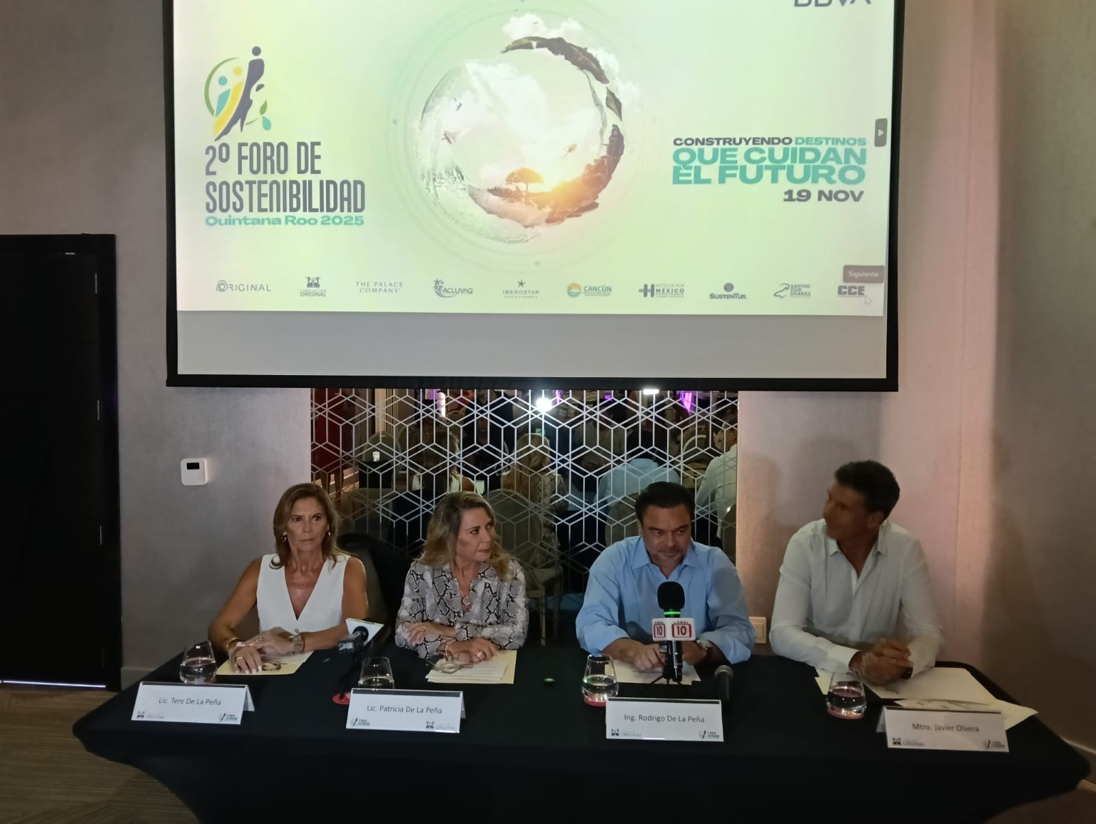 A panel of speakers at the 2nd Sustainability Forum in Quintana Roo, with a presentation backdrop advertising the event.$# CAPTION