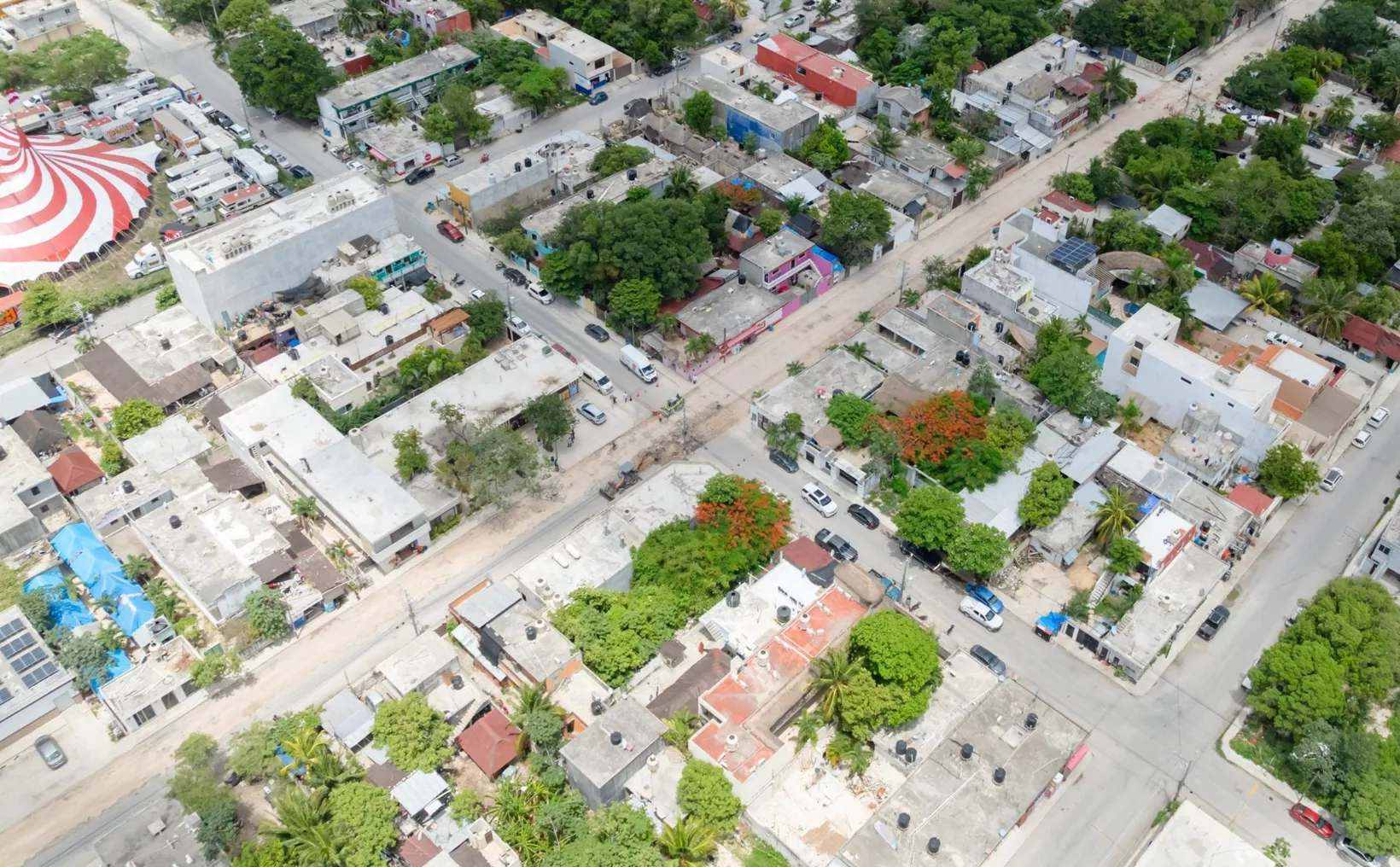 Aerial view showing a residential area with green trees, various buildings, and roads in a tropical setting.$# CAPTION