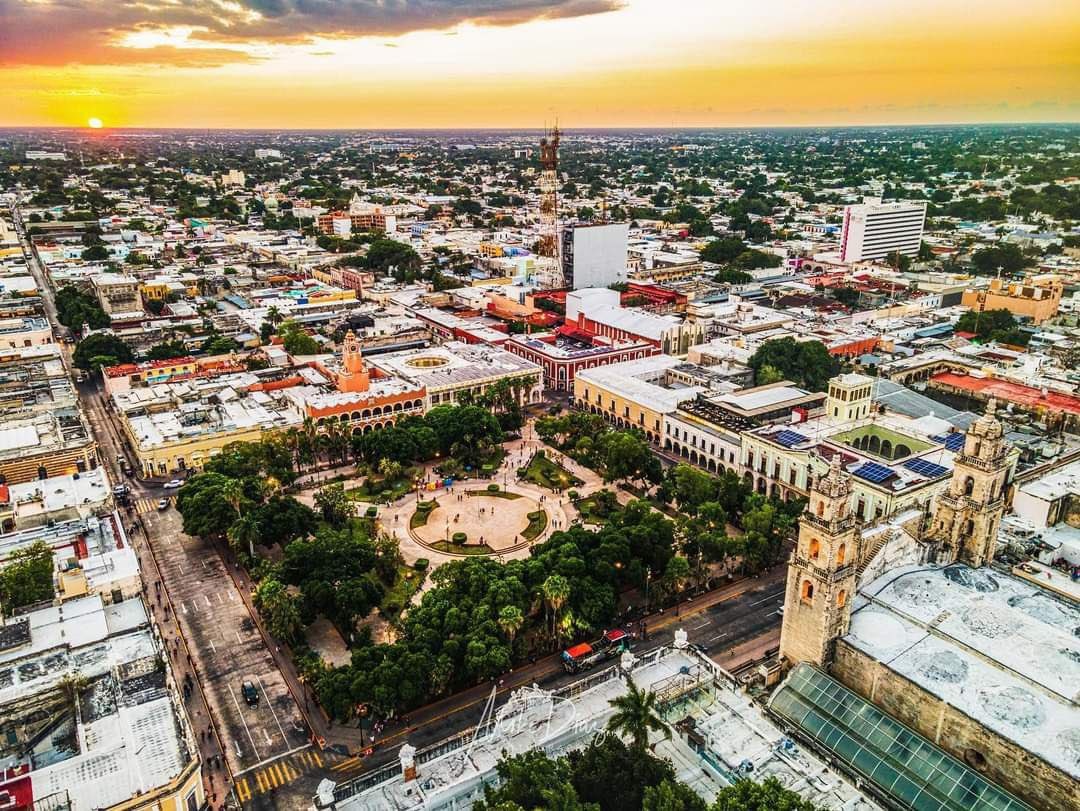 Aerial view of a city featuring a park and colorful buildings during sunset
