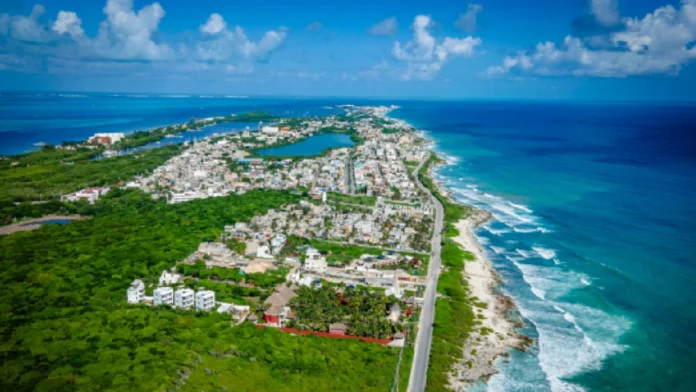 Aerial view showcasing a coastal town with lush greenery, a winding road, and the ocean in the background.$# CAPTION
