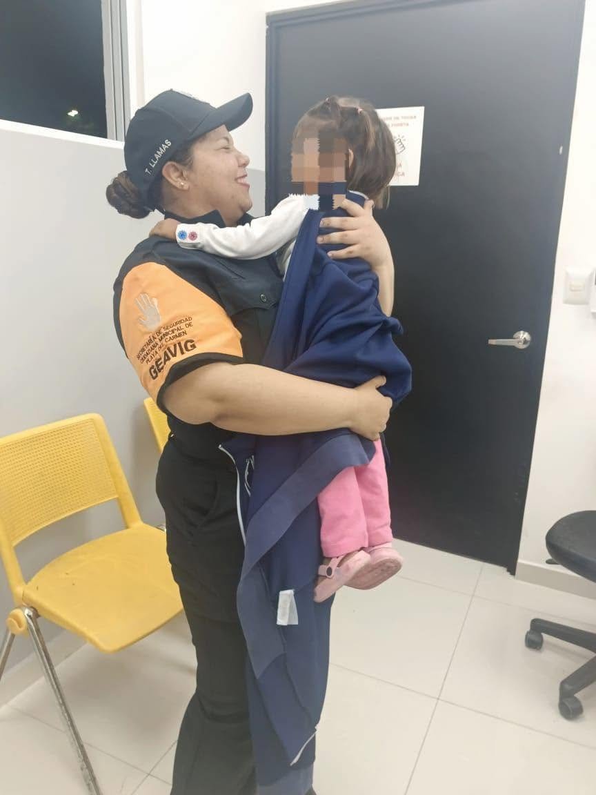 A woman in a uniform joyfully holds a small child wrapped in a blanket in an indoor setting.$# CAPTION