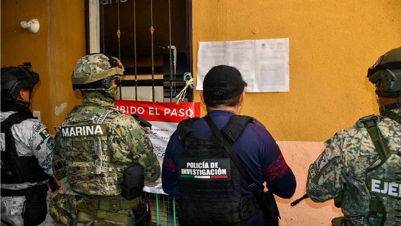 armed personnel examining a notice on a wall in front of a barred window-$# CAPTION
