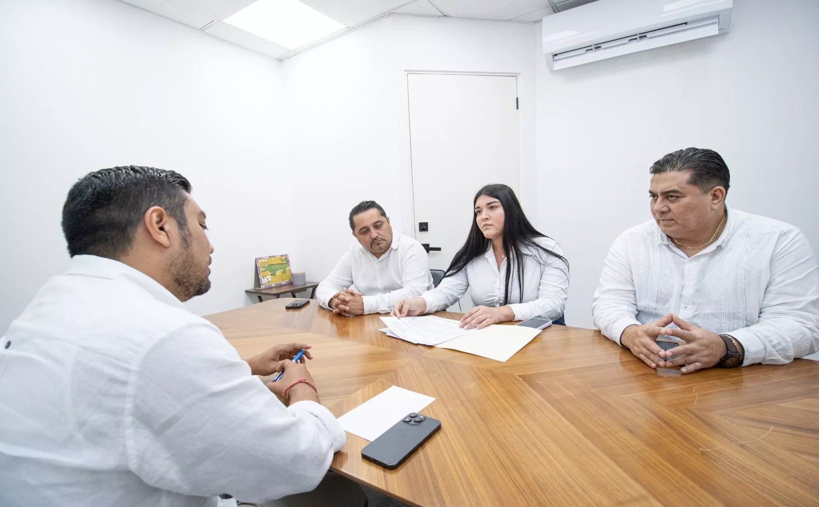Four individuals engaged in a serious discussion during a business meeting in a modern office setting.$# CAPTION