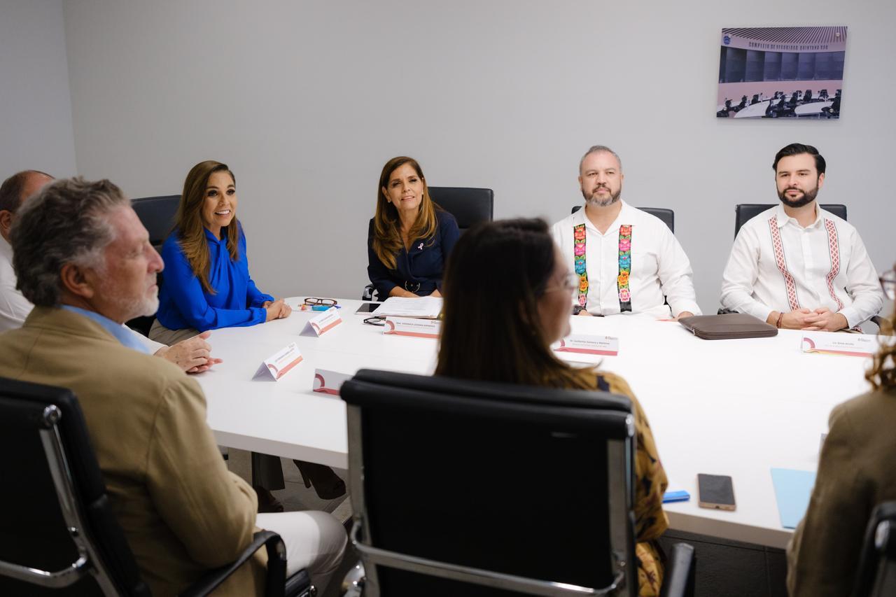 A group of professionals engaged in a meeting at a conference table, with various notes and documents present on the table. The setting appears modern and collaborative.