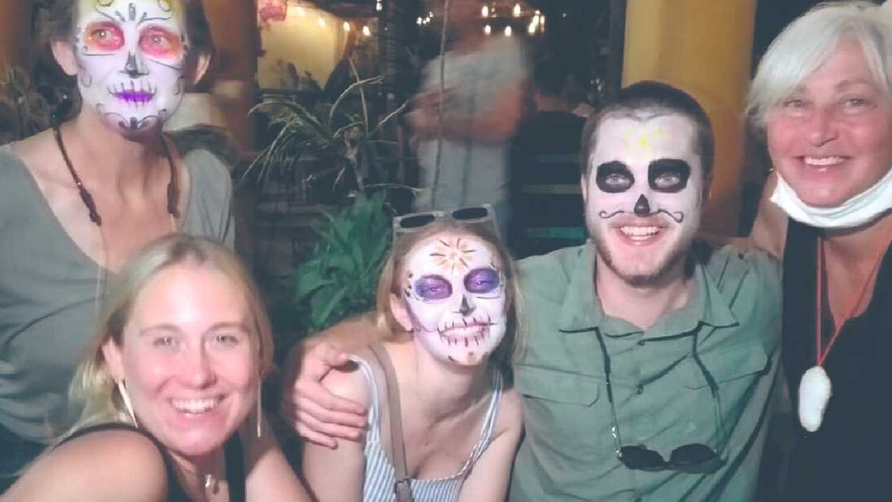 Group of five people with colorful face paint smiling together at a festive event