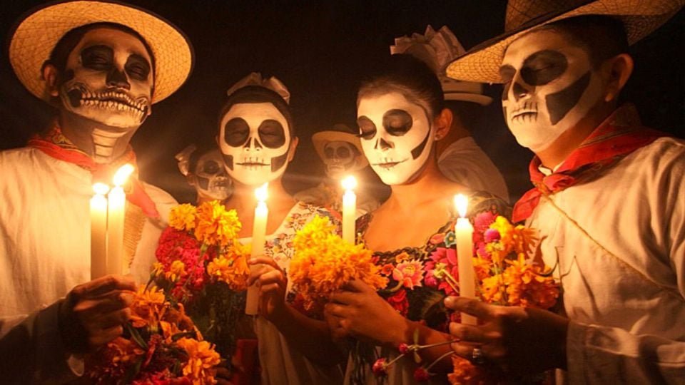 group of people with skull makeup holding candles and flowers in a dark setting