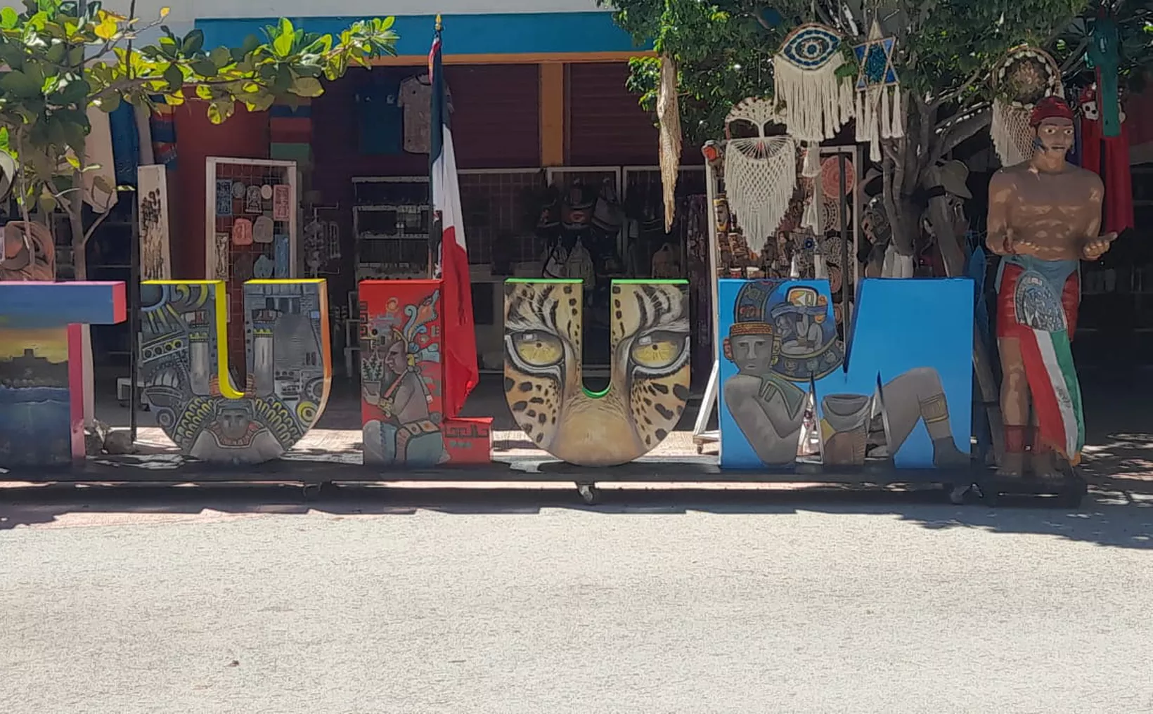 A vibrant street art display spelling "TULUM" with artistic representations of local culture in each letter.$# CAPTION