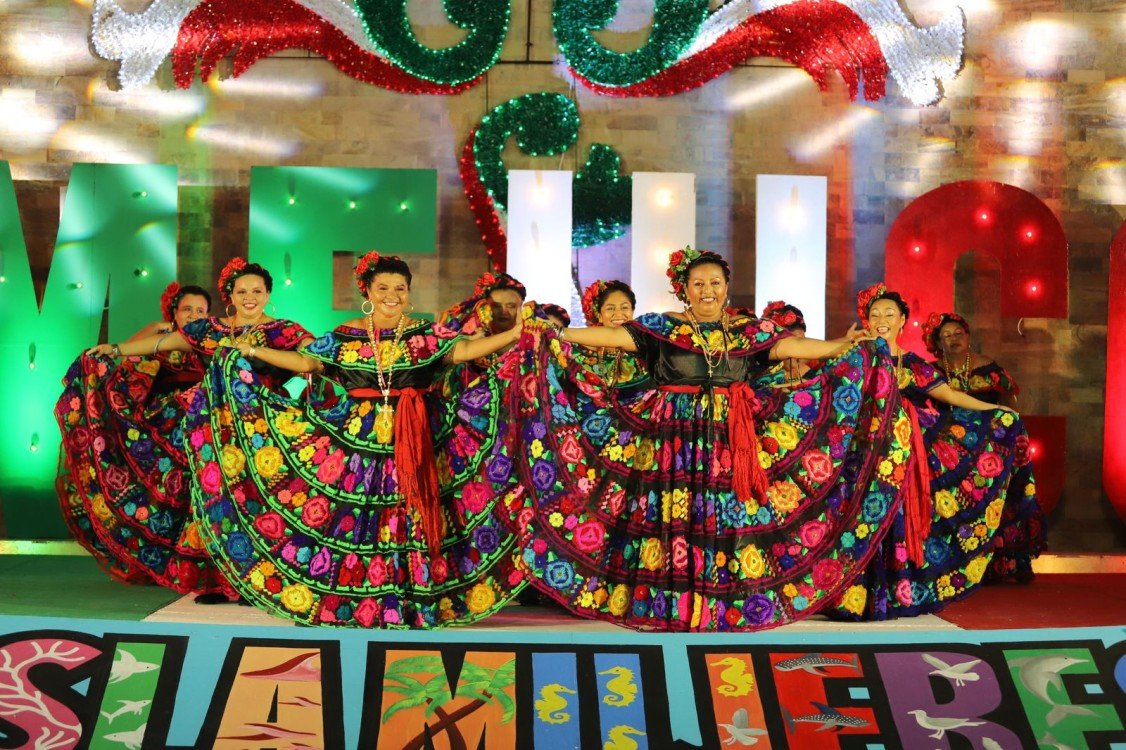 Dancers showcase their cultural heritage through a vibrant performance, wearing traditional costumes adorned with flowers during a festive event.