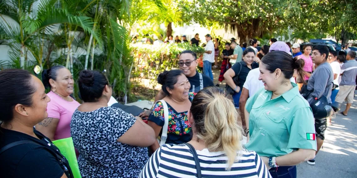 A diverse group of women engaging in conversation at a community event, with vibrant greenery in the background.$# CAPTION