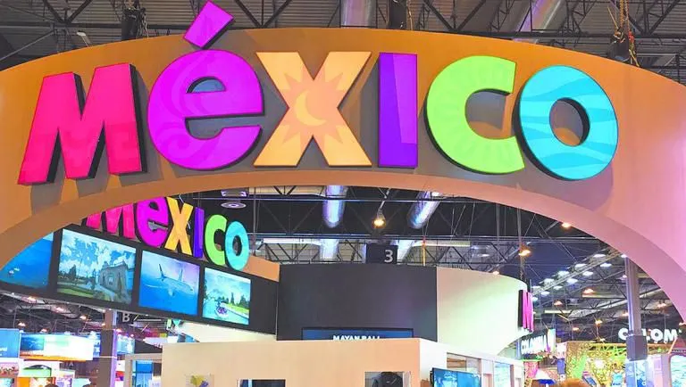 Vibrant sign reading 'México' at a travel exhibition, surrounded by images of landscapes and cultural displays