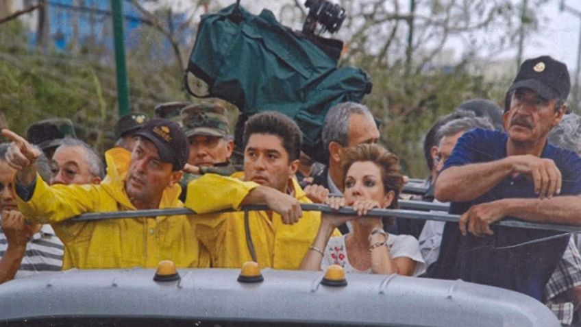 A group of individuals in yellow raincoats and casual clothing, observing a situation from a vehicle. They appear engaged and serious, with a camera setup in the background.