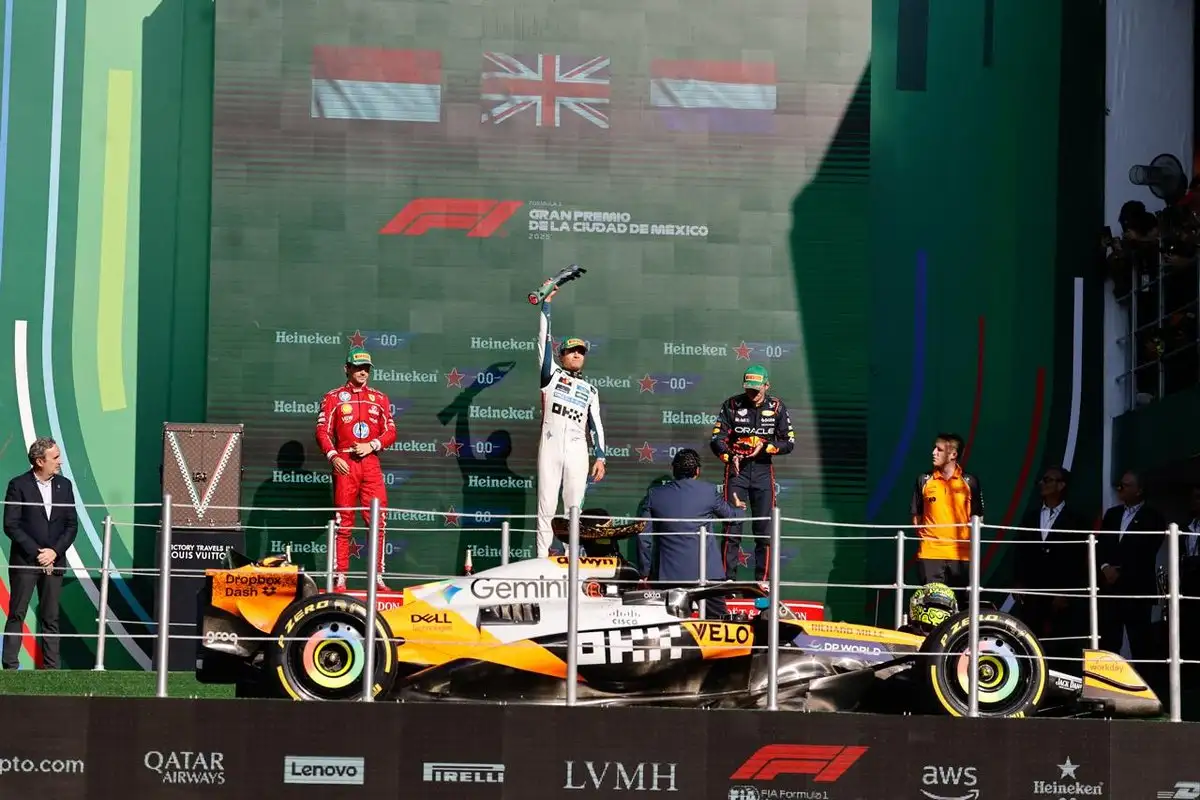 Formula One drivers celebrating on the podium at the Mexican Grand Prix with flags in the background