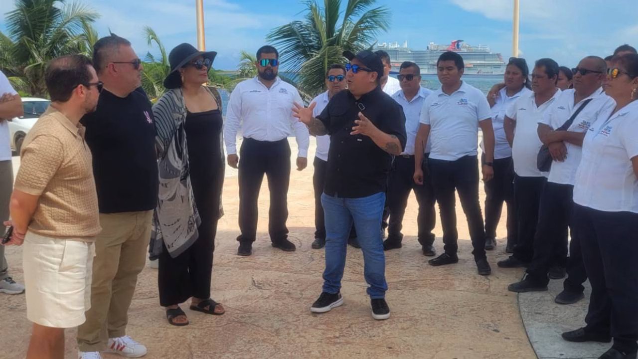 a group of people engaging in a discussion near the ocean with palm trees in the background