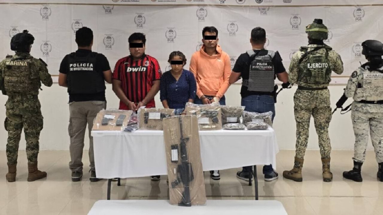 a group of law enforcement officials and suspects with seized weapons on a table-21102025