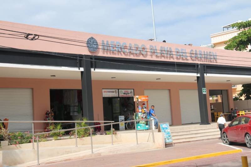 Exterior view of Mercado Playa del Carmen featuring a modern building with closed shutters and signage.$# CAPTION