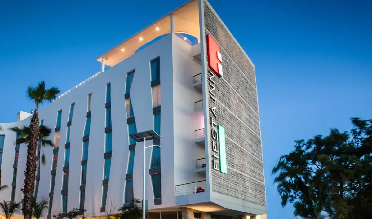 Exterior view of a modern hotel building at dusk, featuring distinctive architectural design and signage.$# CAPTION