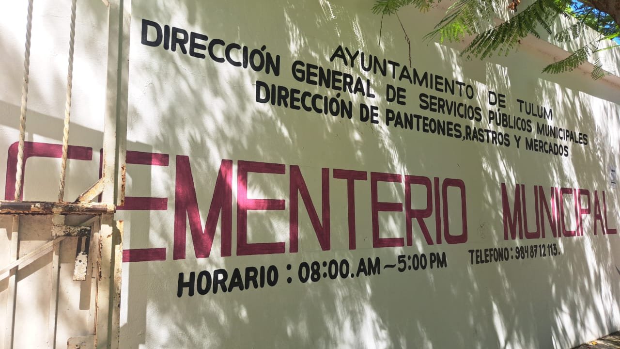 A sign indicating the Municipal Cemetery in Tulum, displaying operating hours and contact information.$# CAPTION
