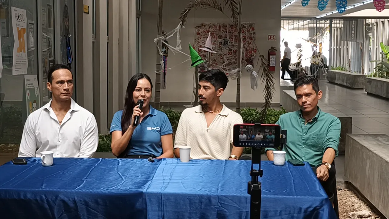 A panel discussion featuring four individuals seated at a blue table in a bright, modern environment, with one person speaking into a microphone.$# CAPTION