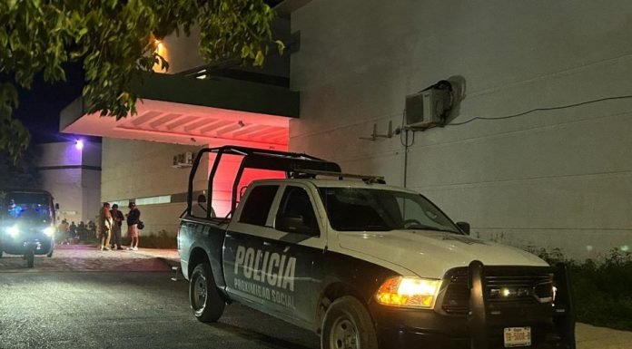 A police vehicle is parked in front of a building at night, with people nearby. Red and purple lights illuminate the scene.$# CAPTION