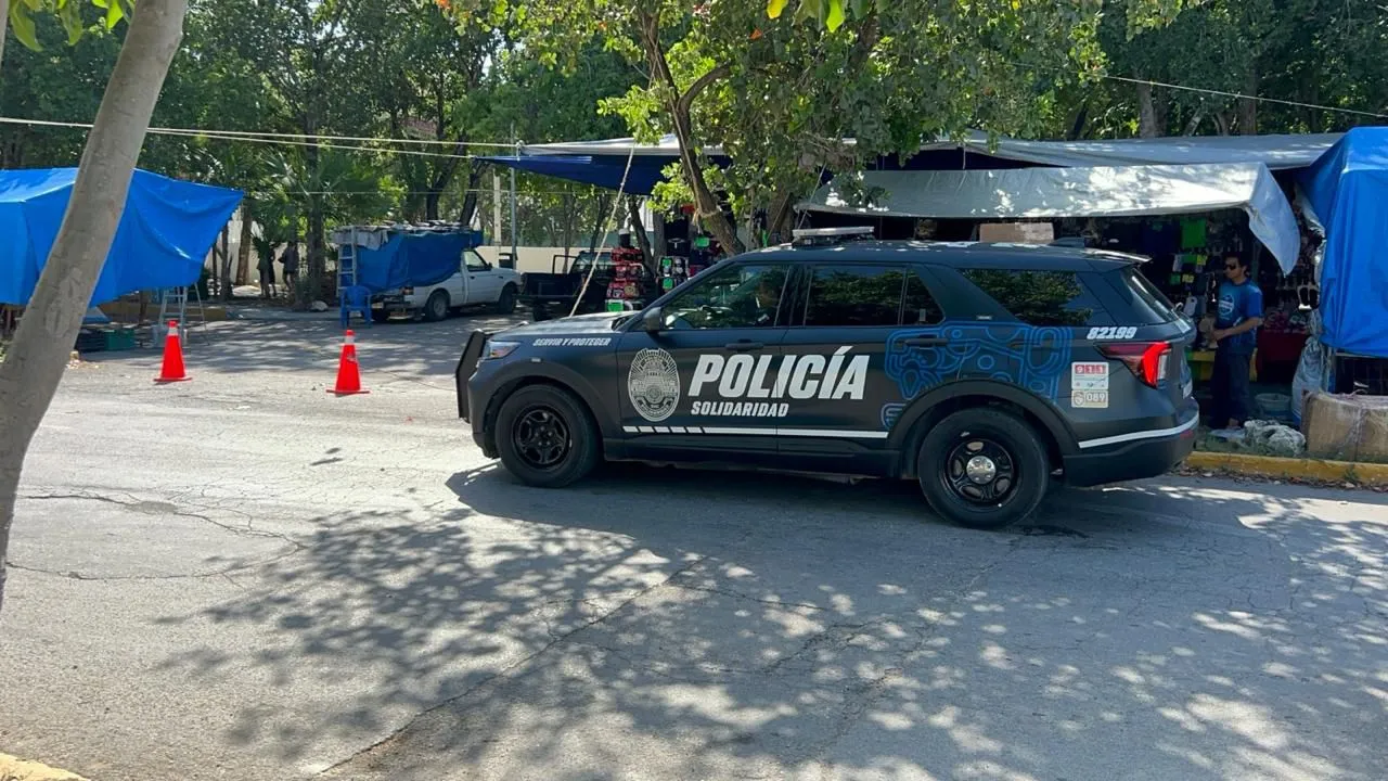 A police vehicle parked near a market area with blue tarps and cones in the background.$# CAPTION