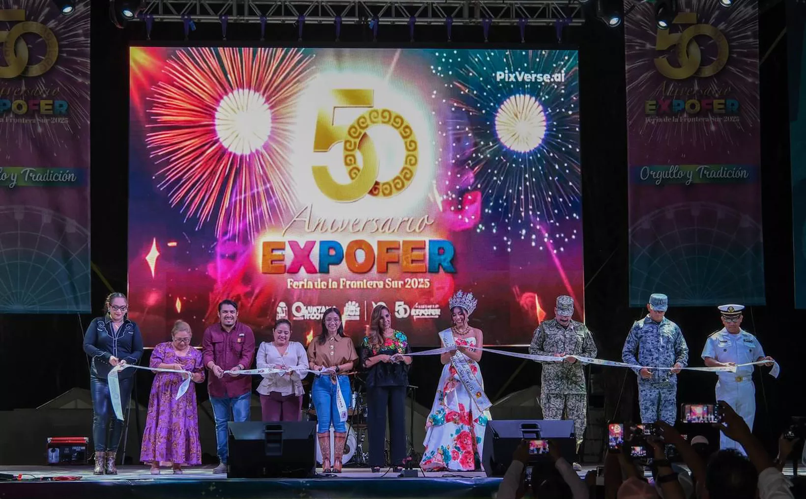 A group of people, including officials in military uniforms and a beauty queen, performing a ribbon-cutting ceremony on stage at the EXPOFER event with a colorful background of fireworks and the event logo.$#$ CAPTION