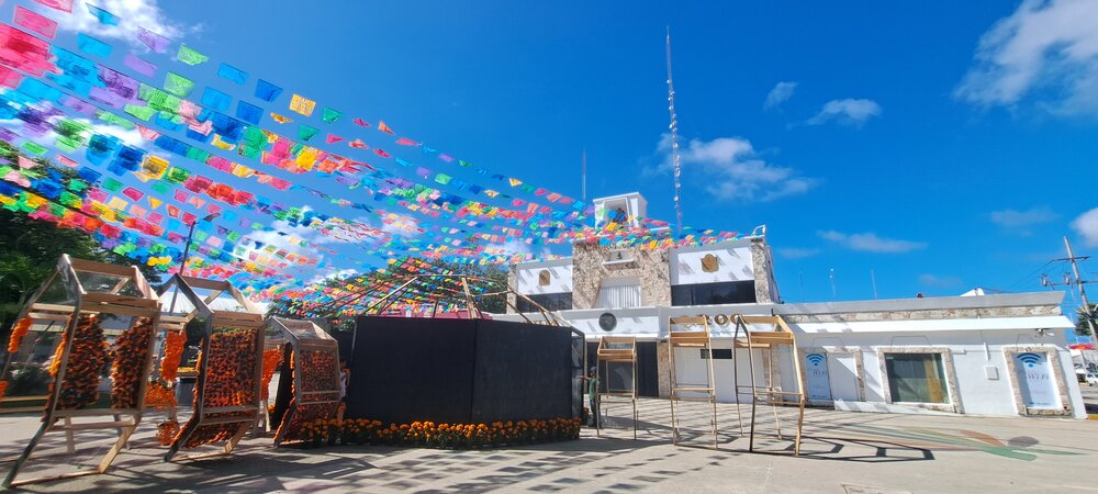 A colorful display of decorations with flags and marigold arrangements in a town square under a clear blue sky.$#$ CAPTION