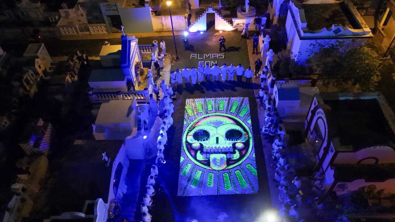 aerial view of a colorful altar with a decorated skull surrounded by participants in white clothing-31102025