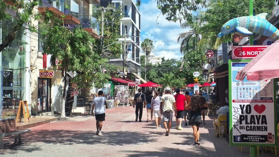 a busy street scene in Playa del Carmen with shops and people walking-30102025