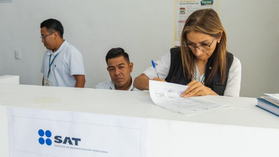 people working at a government office reception desk writing and attending to paperwork