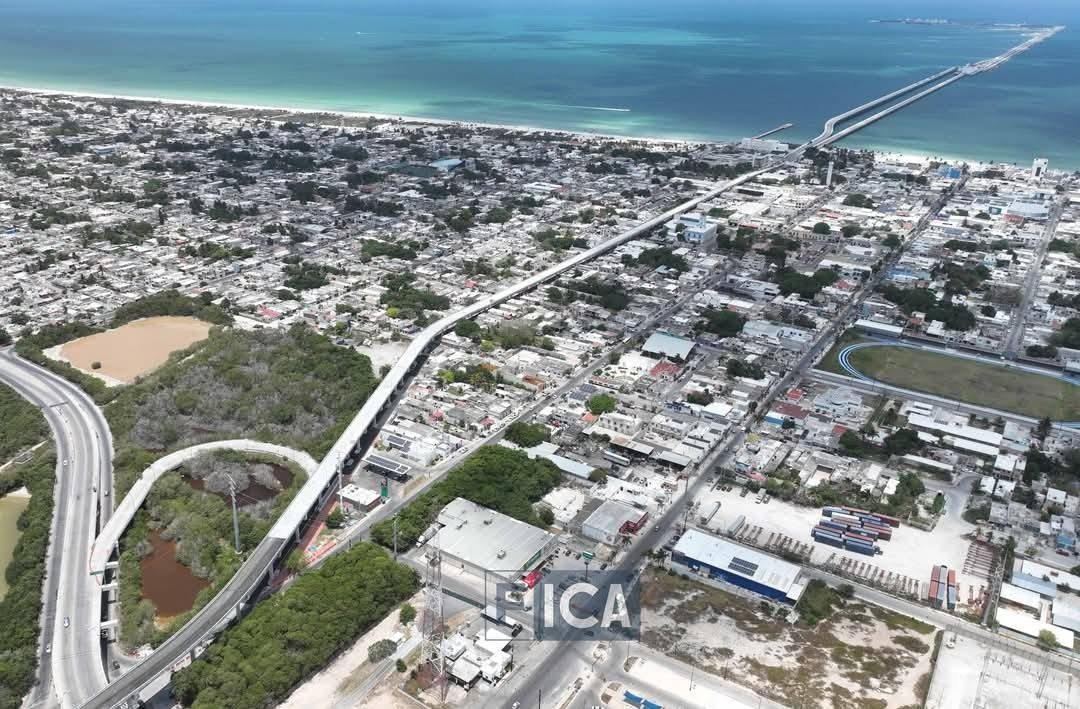 Aerial view of a coastal city showing residential areas, roads, and a bridge extending into the sea