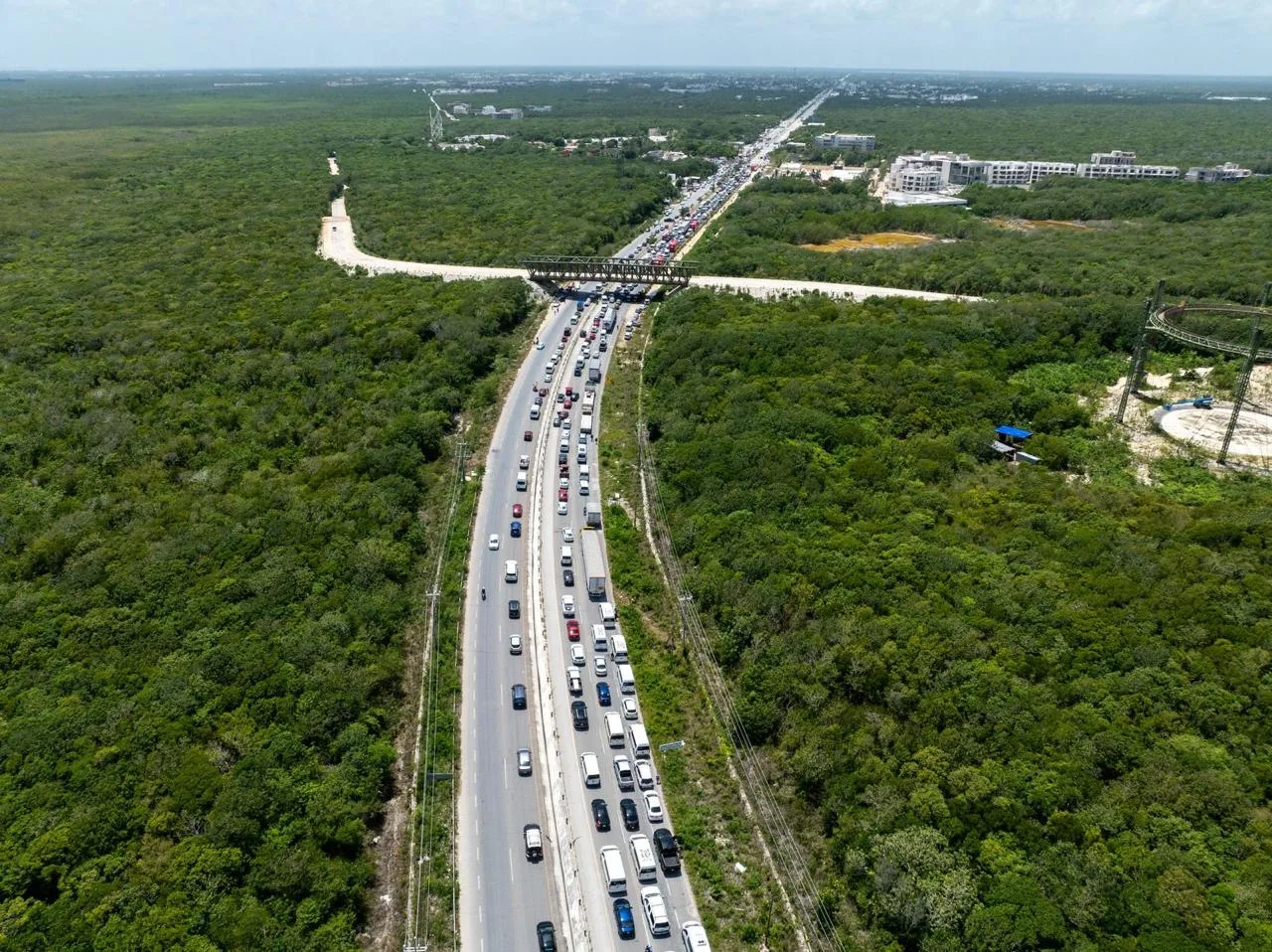 aerial photograph showing a traffic jam on a road surrounded by lush green vegetation and trees