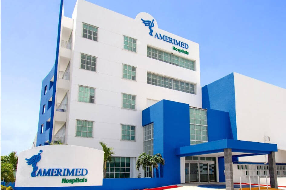 Exterior view of Amerimed Hospital with a blue and white facade and a clear sky in the background.$#$ CAPTION