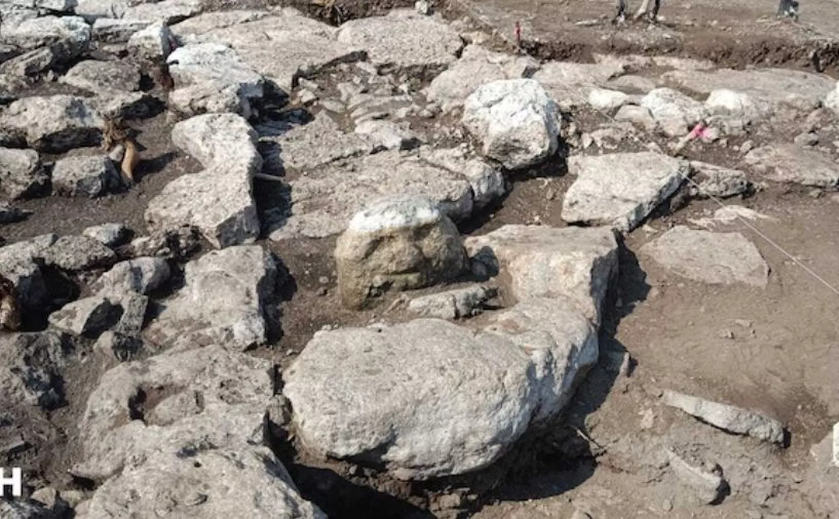 Excavation site showing large stone slabs and structures in the ground