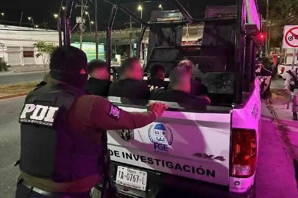 Law enforcement officers conducting an arrest operation with individuals in custody in the back of a police vehicle at night.$#$ CAPTION