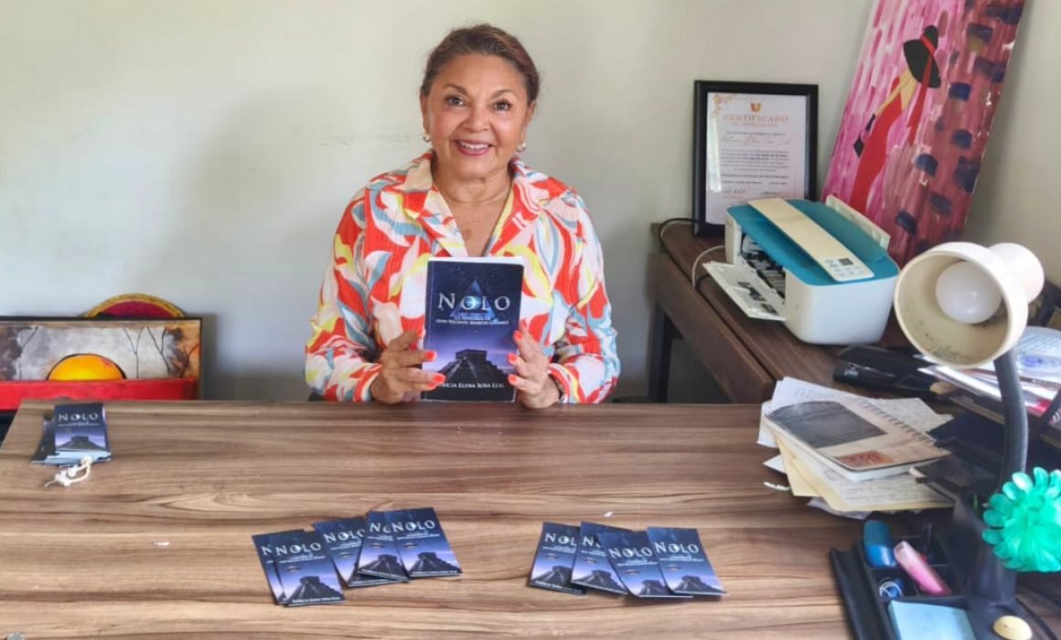 An author smiling while holding her book titled "Nolo," surrounded by additional copies on a table.