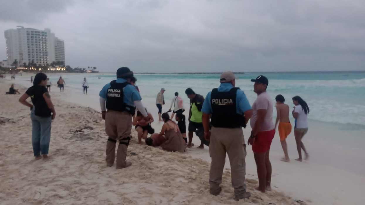 Police officers interacting with beachgoers near the shore while others enjoy the beach in the background.$# CAPTION