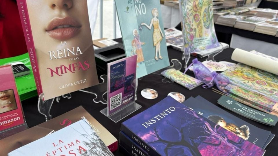 a selection of books displayed on a table at a literary event including titles like La Reina de las Niñas and Instinto